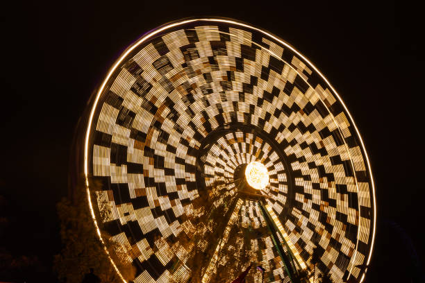 ruota panoramica in movimento al parco divertimenti, illuminazione notturna. lunga esposizione. - ferris wheel wheel blurred motion amusement park foto e immagini stock