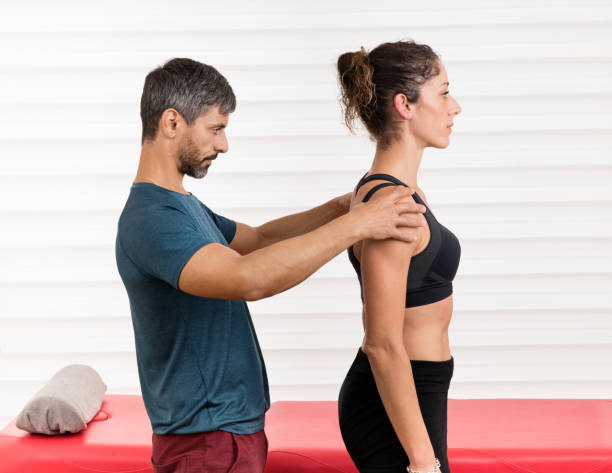 Male osteopath doing a postural evaluation Male osteopath doing a postural evaluation on a young female patient assessing the alignment of her vertebrae and spine in an alternative medicine and healthcare concept posture photos stock pictures, royalty-free photos & images