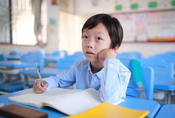 istock Young boy reading at his desk in a classroom 1188160242