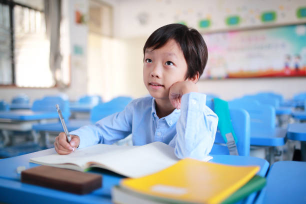 istock Young boy reading at his desk in a classroom 1188160759