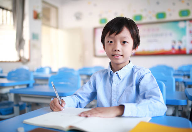 istock Young boy reading at his desk in a classroom 1188160770