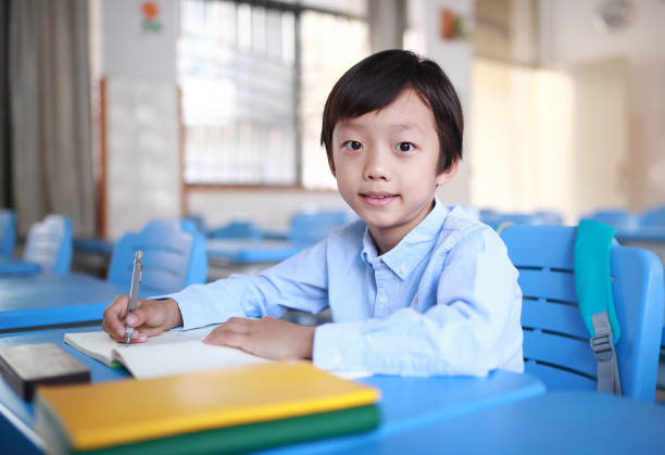 istock Young boy reading at his desk in a classroom 1188160791