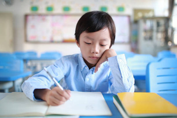 istock Young boy reading at his desk in a classroom 1188160797