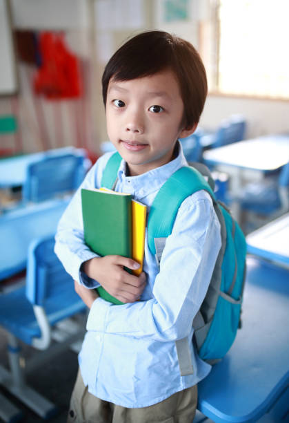 istock Young boy reading at his desk in a classroom 1188161254