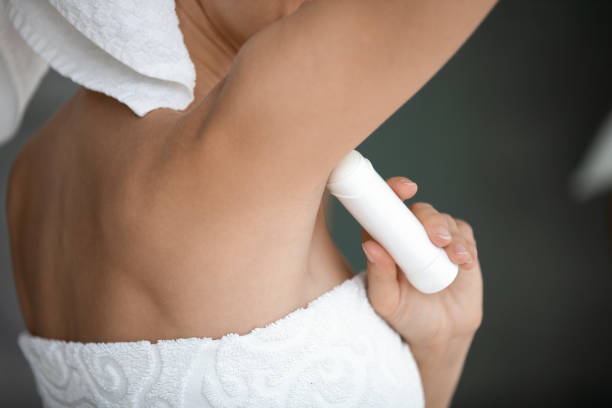 giovane donna avvolta in asciugamano bianco applicare antitraspirante in ascella - bloccato foto e immagini stock