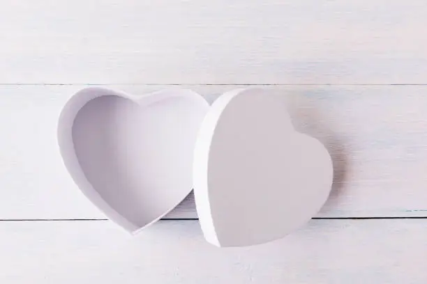Photo of Empty open heart shaped gift box over white wooden background