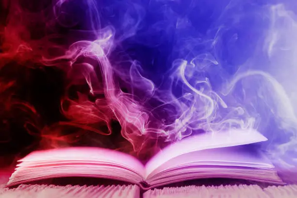 Open book with magic light and colored smoke