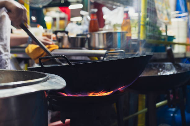 夜市の屋外ガス中華鍋で調理するストリートフードシェフのクローズアップ - thai cuisine wok food thai culture ストックフォトと画像