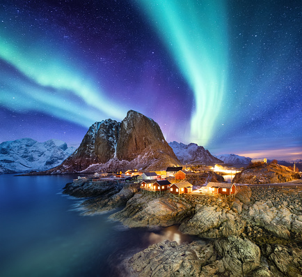 Aurora Boreal está por encima de Reine, islas Lofoten, Noruega. No continuación, la luz, las montañas y las casas. Paisaje de invierno por la noche. Viajes a Noruega - imagen photo