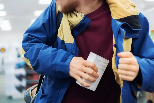 Photo of close up consumer  thiefâs hands putting the new gadget in the pocket in the store