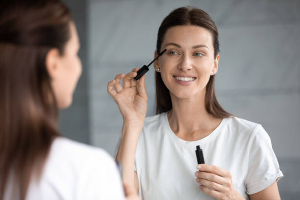 istock Happy attractive woman applying mascara on eyelashes looking in mirror 1188171977