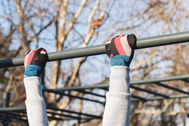 Close-up of female hands in sport gloves are holding onto a horizontal bar. stock photo