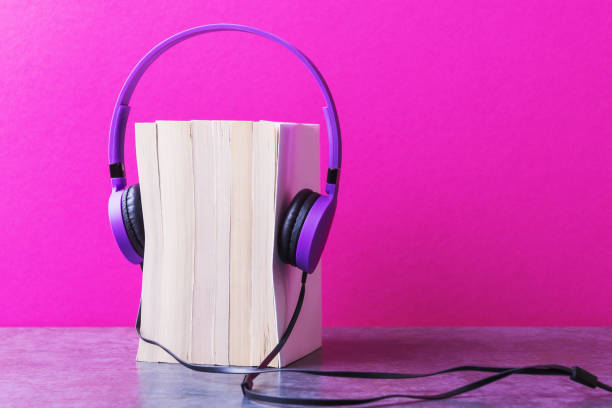 istock Stack of books with violet headphones over pink background 1188173235