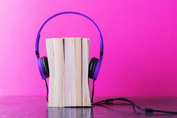 istock Stack of books with violet headphones on pink background 1188173255