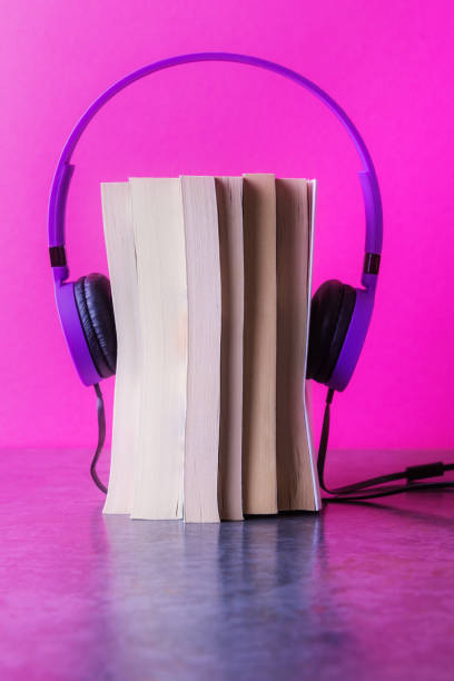 istock Stack of books with violet headphones on pink background 1188173269