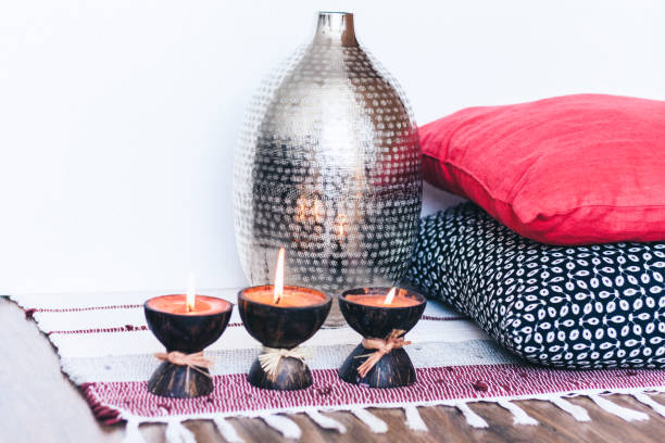 istock Burning spa aroma candle in coconut shell, decorative pillows and vase on multi-colored rug background, cozy home interior 1188174616