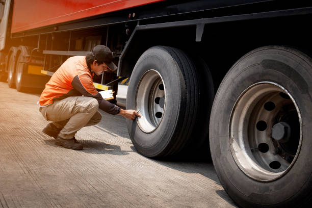 安全を検査するトラック運転手は、トラックの車輪を毎日チェック - flatbed truck truck truck driver heavy ストックフォ�トと画像