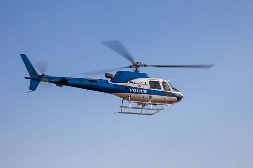 Police helicopter in flight speeding against the blue sky