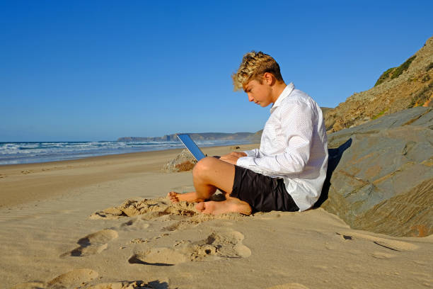 istock Young guy at the beach working on his laptop 1188181784