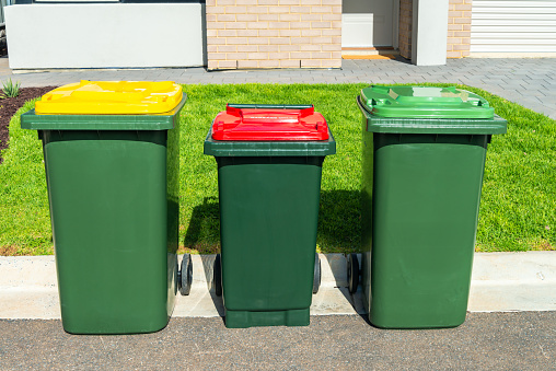 Closeup of garbage and yard waste bins in front of a typical residence in Greater Vancouver, B.C.