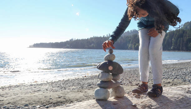 istock Young girl stacks zen rocks on beach 1188189458