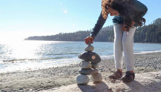 istock Young girl stacks zen rocks on beach 1188189692