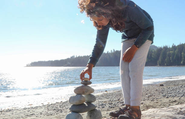 istock Young girl stacks zen rocks on beach 1188189700