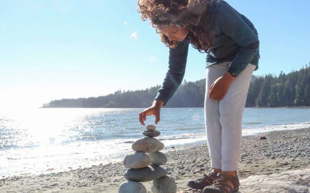istock Young girl stacks zen rocks on beach 1188189769