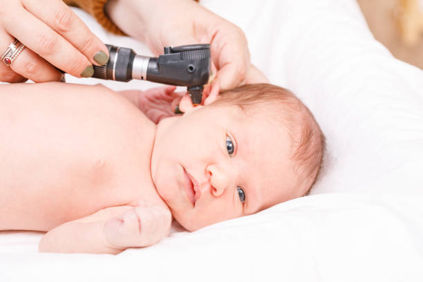 Newborn ENT exam - doctor checking ear with otoscope in pediatric clinic stock photo