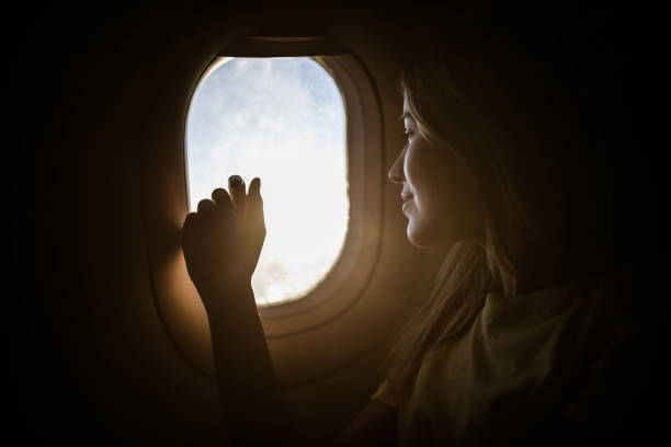 mulher de sorriso que aprecia ao olhar através do indicador do avião. - airplane window indoors looking through window - fotografias e filmes do acervo