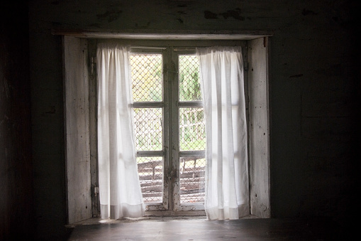 Old window secured with wire mesh  at an abandoned farmhouse