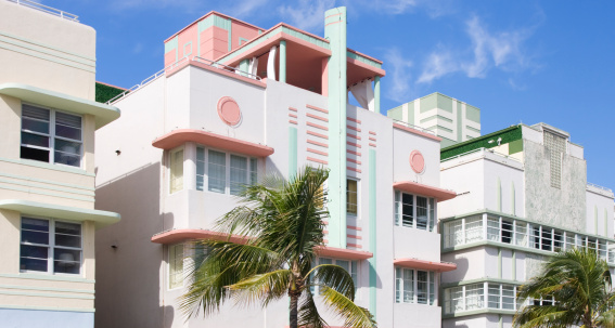 Miami, United States - October 10, 2014: McAlpin Hotel, designed by L. Murray Dixon, 1940, is located at Ocean Drive, in Miami Art Deco District.\n\nThe district is full of beautiful buildings in art deco style from the period between 1930-1942. The area located in South Beach, also known as Old Miami Beach Historic District is a well-visited tourist attraction with its 960 art deco historic buildings.\n\nAt the top of the building, an East Asian descent is making a peace sign to the camera