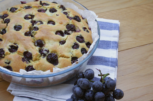 Italian sweet cake called focaccia with black grape on a wooden table
