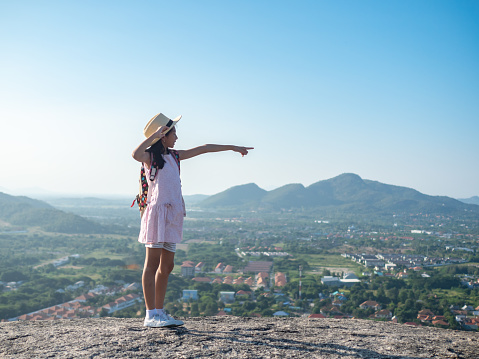 Girl with backpack pointing  on the top of city view, lifestyle concept.