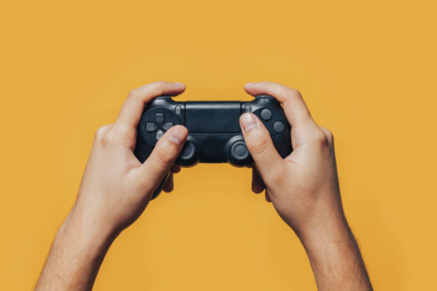 gamepad in hands man gamer hands holding black gamepad on yellow background. computer game control stock pictures, royalty-free photos & images