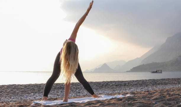 istock Young woman practices yoga on the beach 1188206720