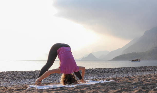 istock Young woman practices yoga on the beach 1188206728