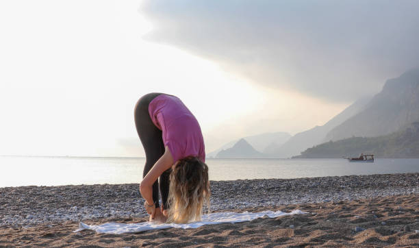 istock Young woman practices yoga on the beach 1188206734
