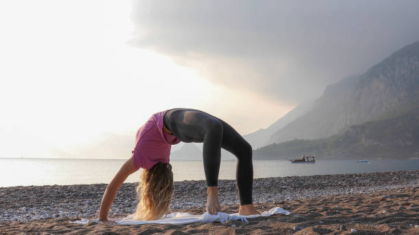 istock Young woman practices yoga on the beach 1188206784