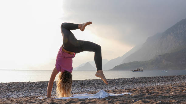 istock Young woman practices yoga on the beach 1188206825