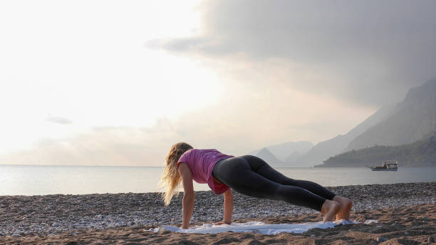 Young woman practices yoga on the beach