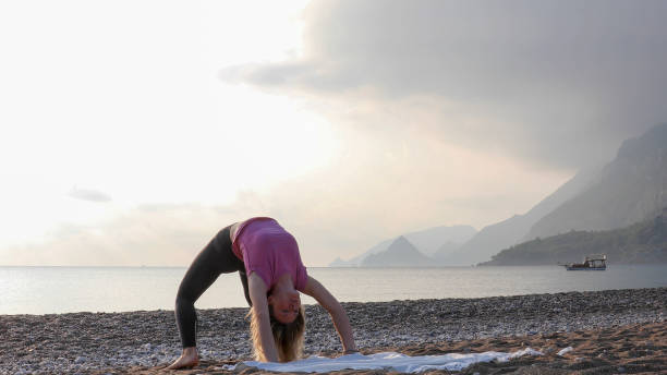 istock Young woman practices yoga on the beach 1188206894
