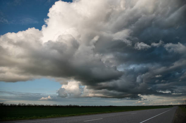 Empty country asphalt road with dramatic voluminous evening clouds before a thunderstorm. Beautiful weather clouds background.
