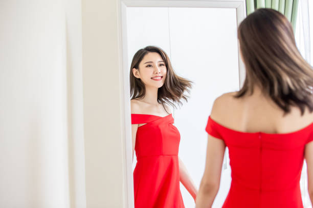 fille asiatique essayant la robe heureusement - mirror women dress looking photos et images de collection