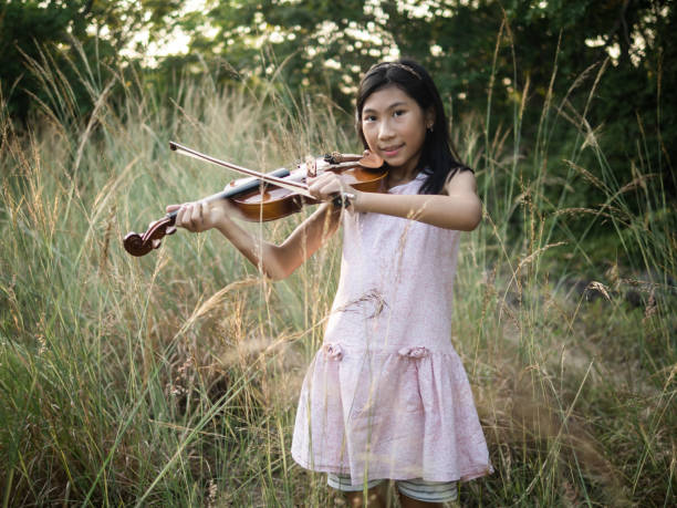 istock Asian girl playing violin in the grass with sun light. 1188214814