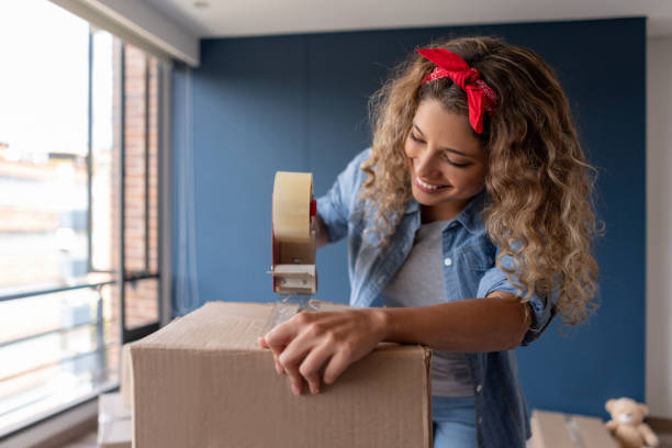 istock Woman moving house and closing a box while packing 1188220413