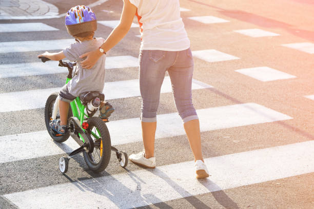 madre con hijo con una bicicleta en una cebra - familia de cruzar la calle fotografías e imágenes de stock