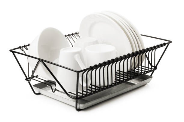 Clean dishes drying on metal dish rack, isolated on white background
