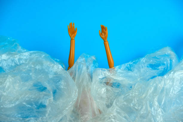ビニール袋の山から突き出たプラスチック人形の手 - cleaning environment clean earth ストックフォトと画像
