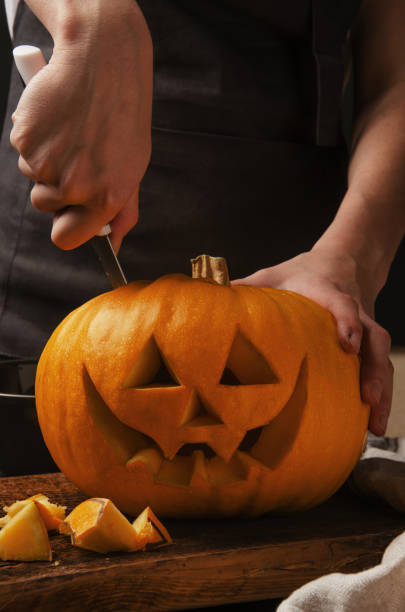 istock Hands cutting, carving pumpkin into jack-o-lanterns for halloween 1188229506